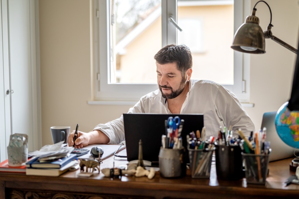 man-with-earphones-having-conference-call-online-sitting-at-home-office-with-laptop-working-from-home_t20_xXNB0B