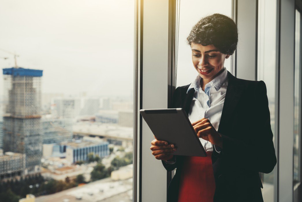 a-cheerful-young-african-american-businesswoman-is-reading-company-news-on-a-tablet-pc-screen-while_t20_O0Bj4E